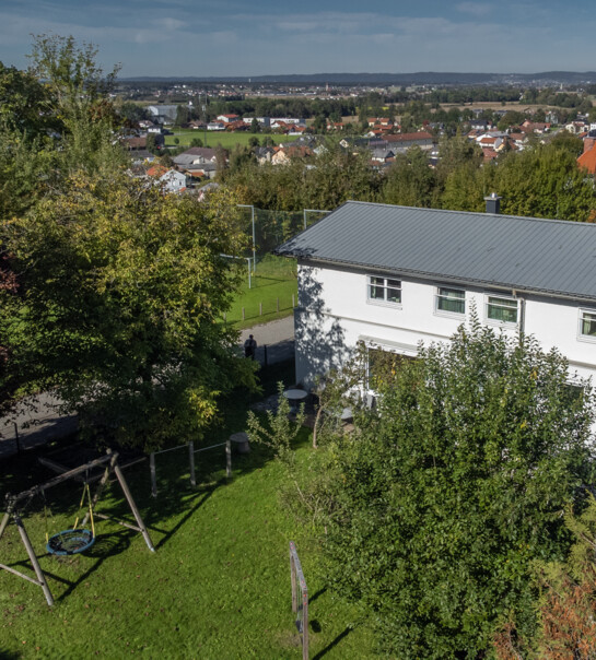 Außenansicht der Wohngemeinschaft mit Garten und Schaukel.