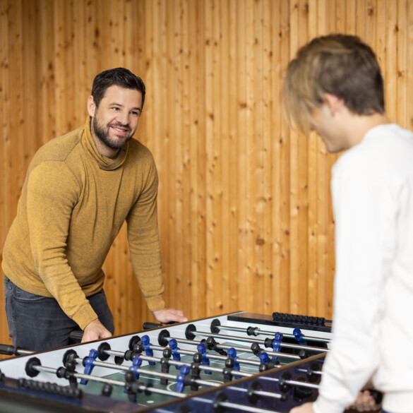 Sozialpädagoge spielt Tischfußball mit einem Jugendlichen.