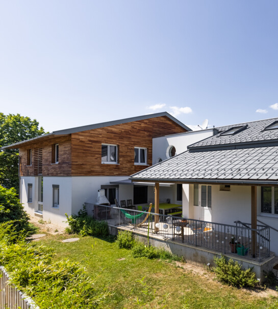 Außenansicht der Wohngemeinschaft mit Garten und erhöhtem, überdachtem Podium mit Esstisch.