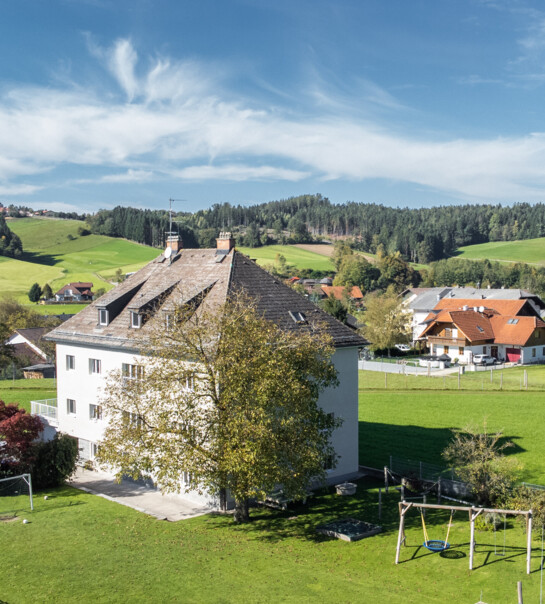 Außenansicht der Wohngemeinschaft mit großem Garten und Schaukel.